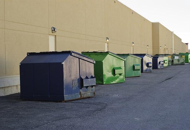 a construction worker empties a wheelbarrow of waste into the dumpster in Austell, GA